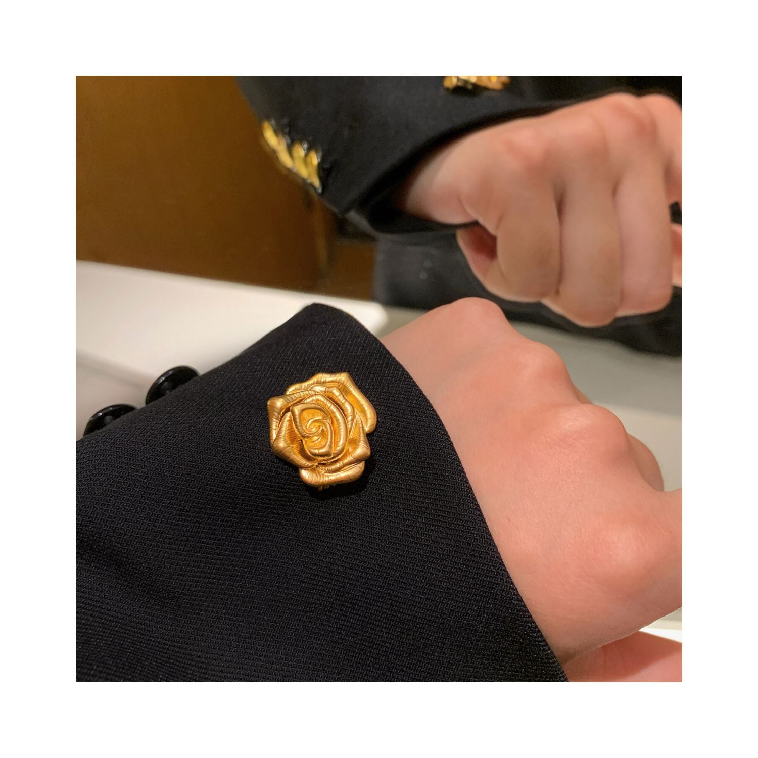 A Rose Is a Rose rose flower brooch styled on a dark lapel, featuring a dimensional bloom silhouette and polished gold-tone finish.