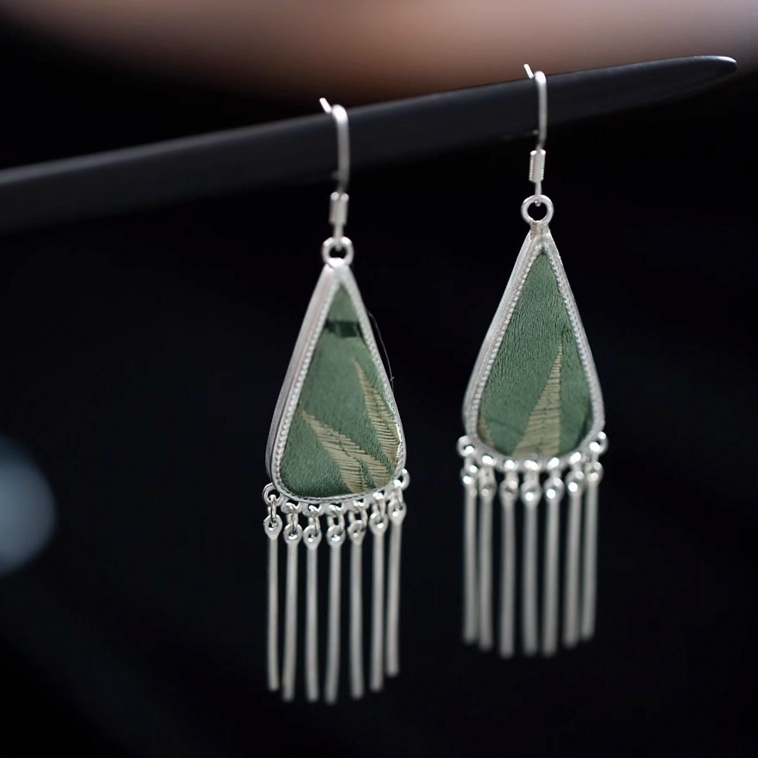 Bamboo green Song Brocade triangle fringe dangle earrings with long silver-tone fringe on a dark background.