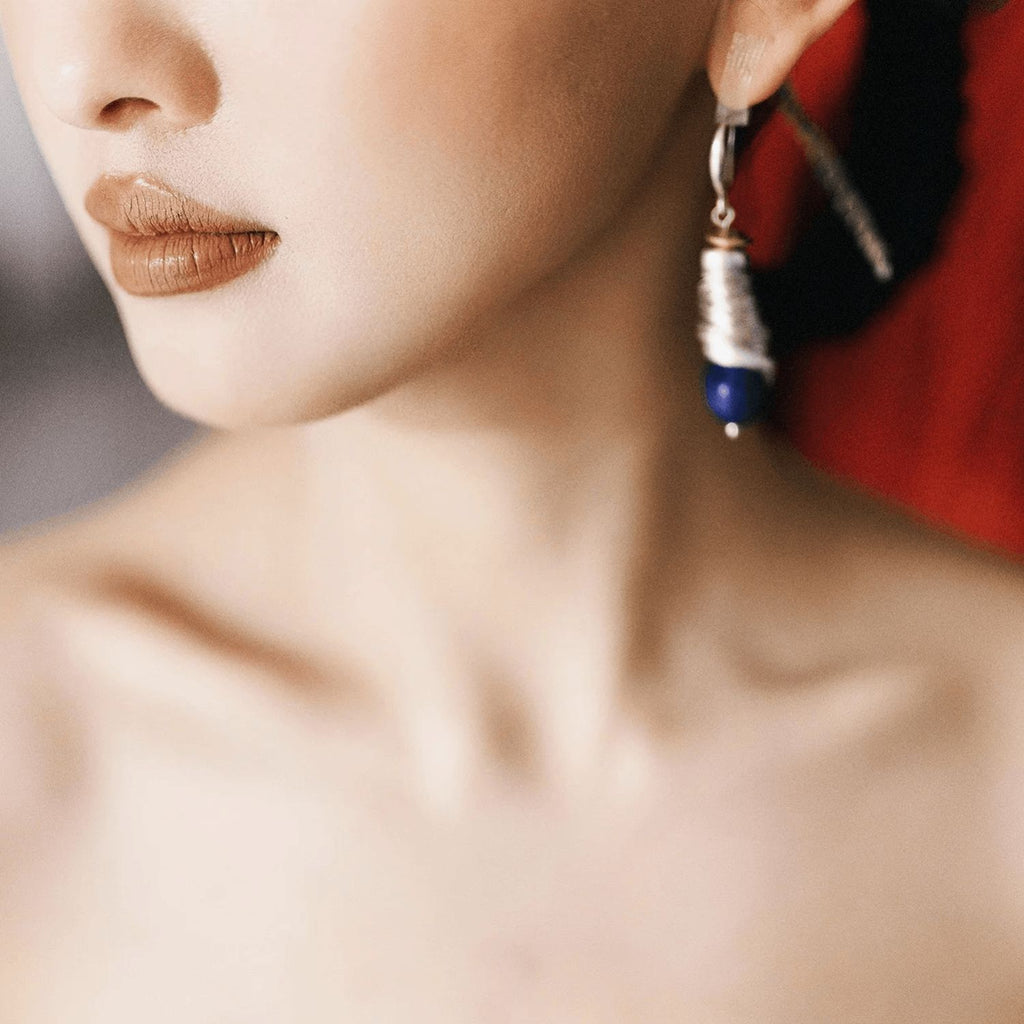 Model wearing Celestial Swirl lapis lazuli spiral silver drop earrings with blue gemstone detail.