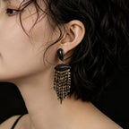 Close-up of ebony wood black and gold fringe drop earrings with layered glass seed bead tassels.