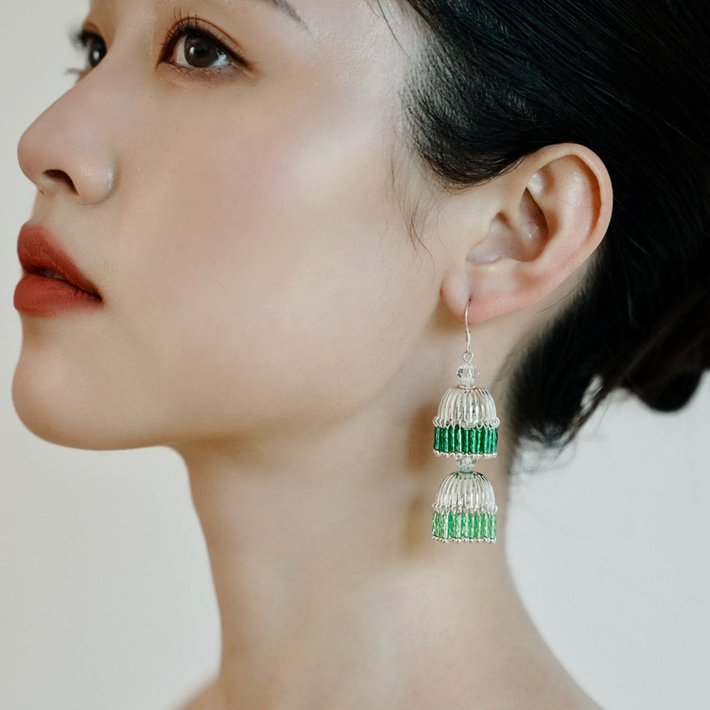 Model wearing green gradient bugle bead lantern drop earrings with a lightweight tiered tassel shape.