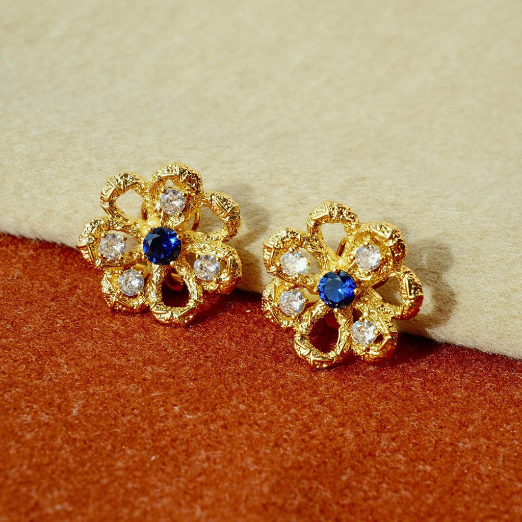 Eternal Blossom gold openwork flower stud earrings with sapphire-blue centre stone and cubic zirconia accents.