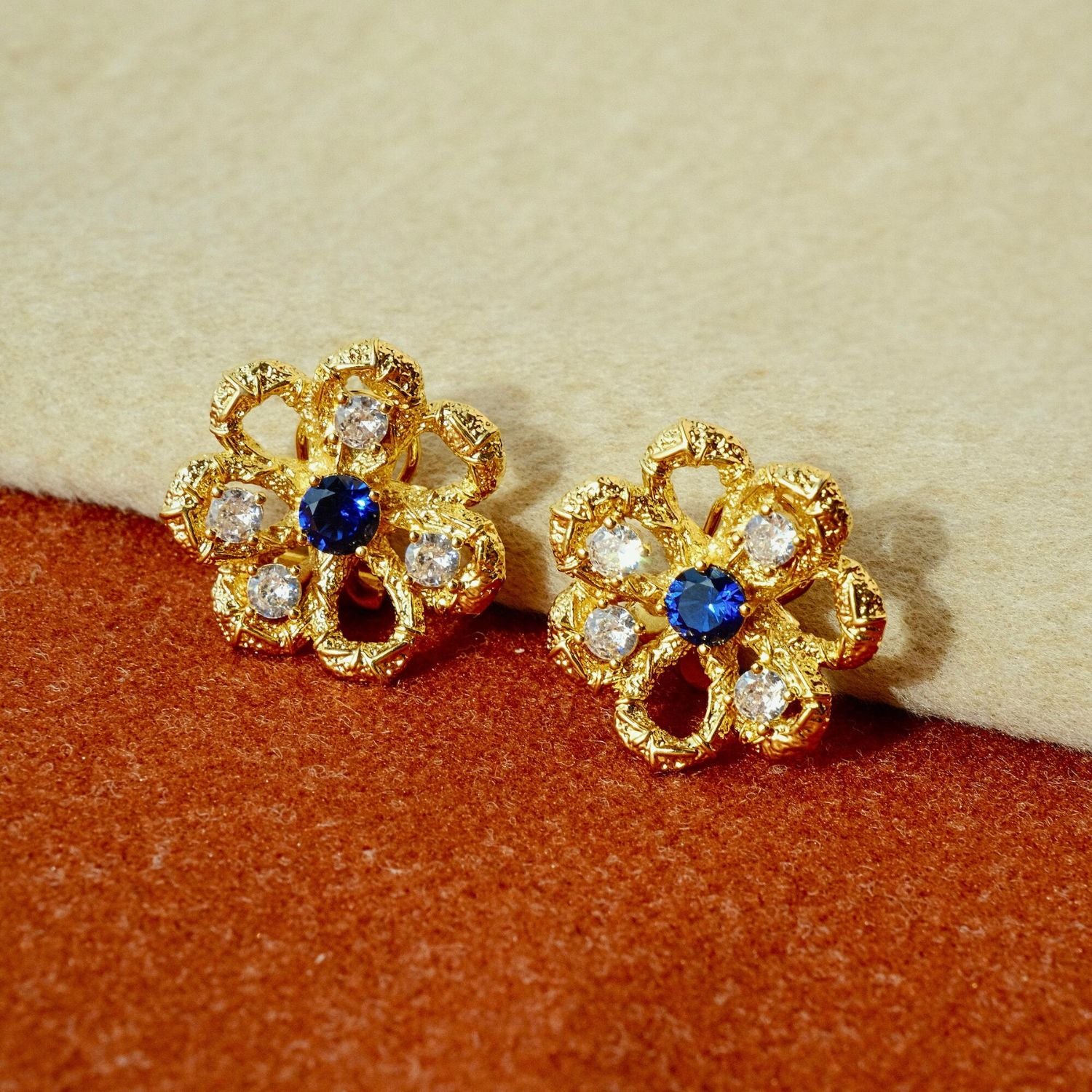 Eternal Blossom gold openwork flower stud earrings with sapphire-blue centre stone and cubic zirconia accents.