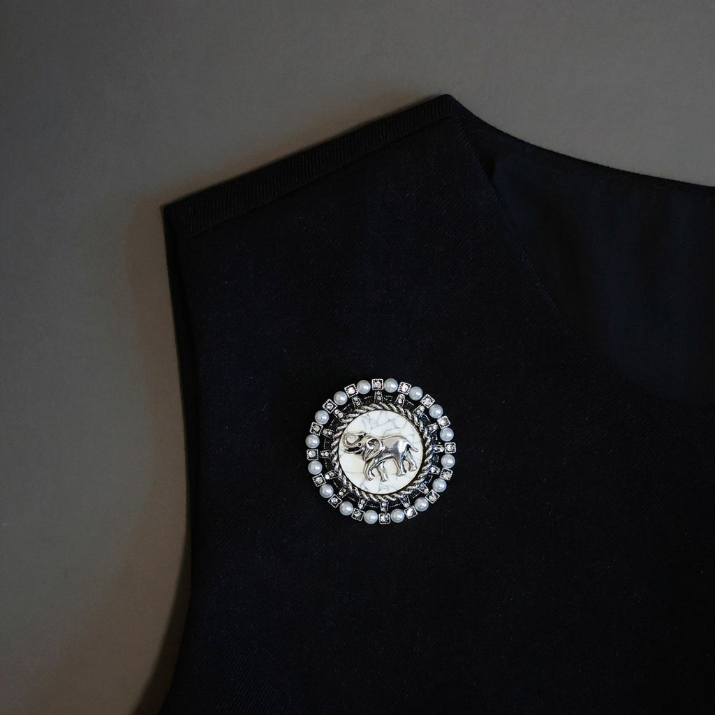 Vintage elephant pearl brooch pinned on a black top, showing scale and lapel styling.