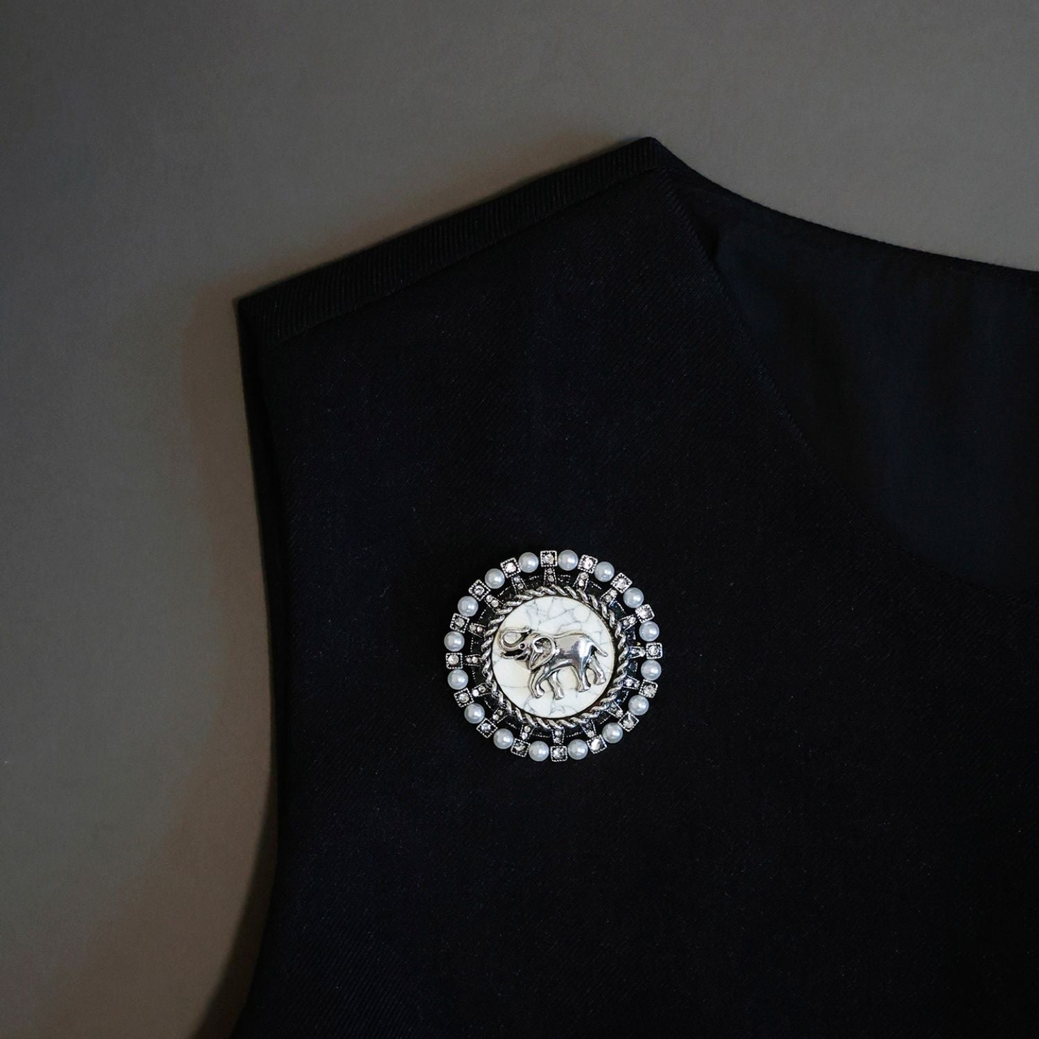Vintage elephant pearl brooch pinned on a black top, showing scale and lapel styling.