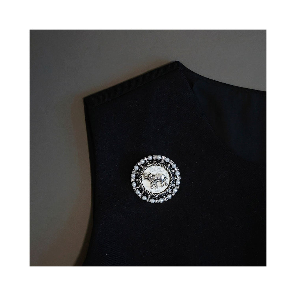 Jinherit Gentle Guardian vintage elephant brooch worn on black clothing, showing round pearl brooch styling for blazers, coats, scarves, or structured bags.