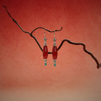 Jinherit Ancient Ember red agate and turquoise drop earrings displayed on a sculptural branch, featuring elongated red agate beads, turquoise accents, and antiqued silver-tone details.
