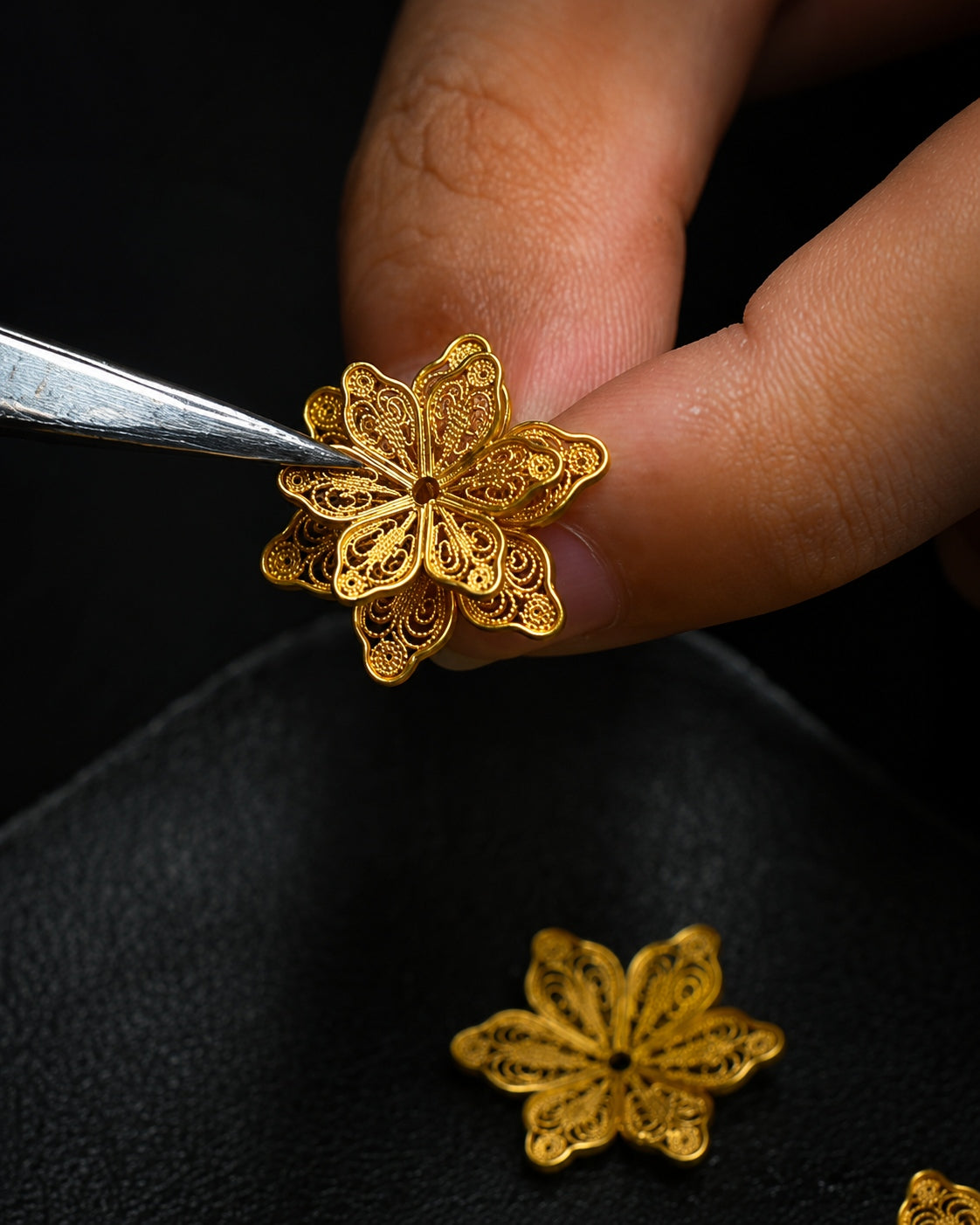 Artisan shaping an intricate gold filigree flower motif by hand for Jinherit Artisan Heritage.