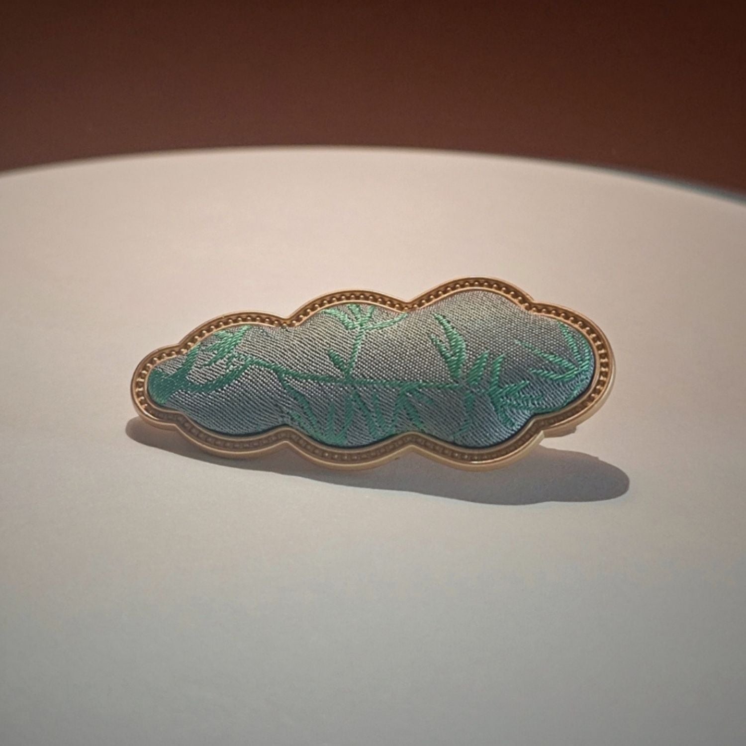 Jinherit Auspicious Cloud Song Brocade silk hair clip in Bamboo Green, showing green woven silk texture, soft brocade sheen, and heritage-inspired cloud motif.