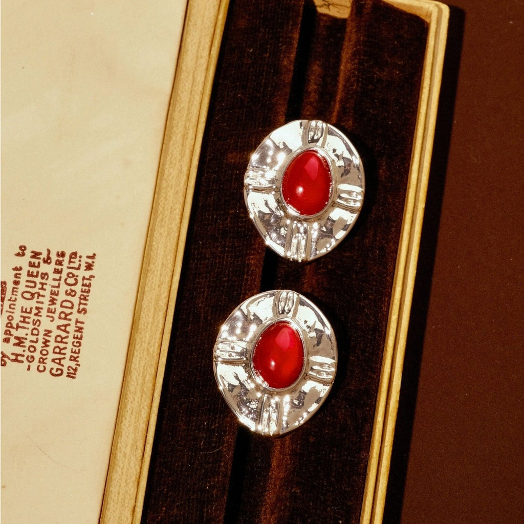 Jinherit Brave Heart red agate and vintage-silver stud earrings displayed in a jewelry box, featuring oval red agate cabochons, hammered silver-plated frames, and a bold medieval-inspired look.