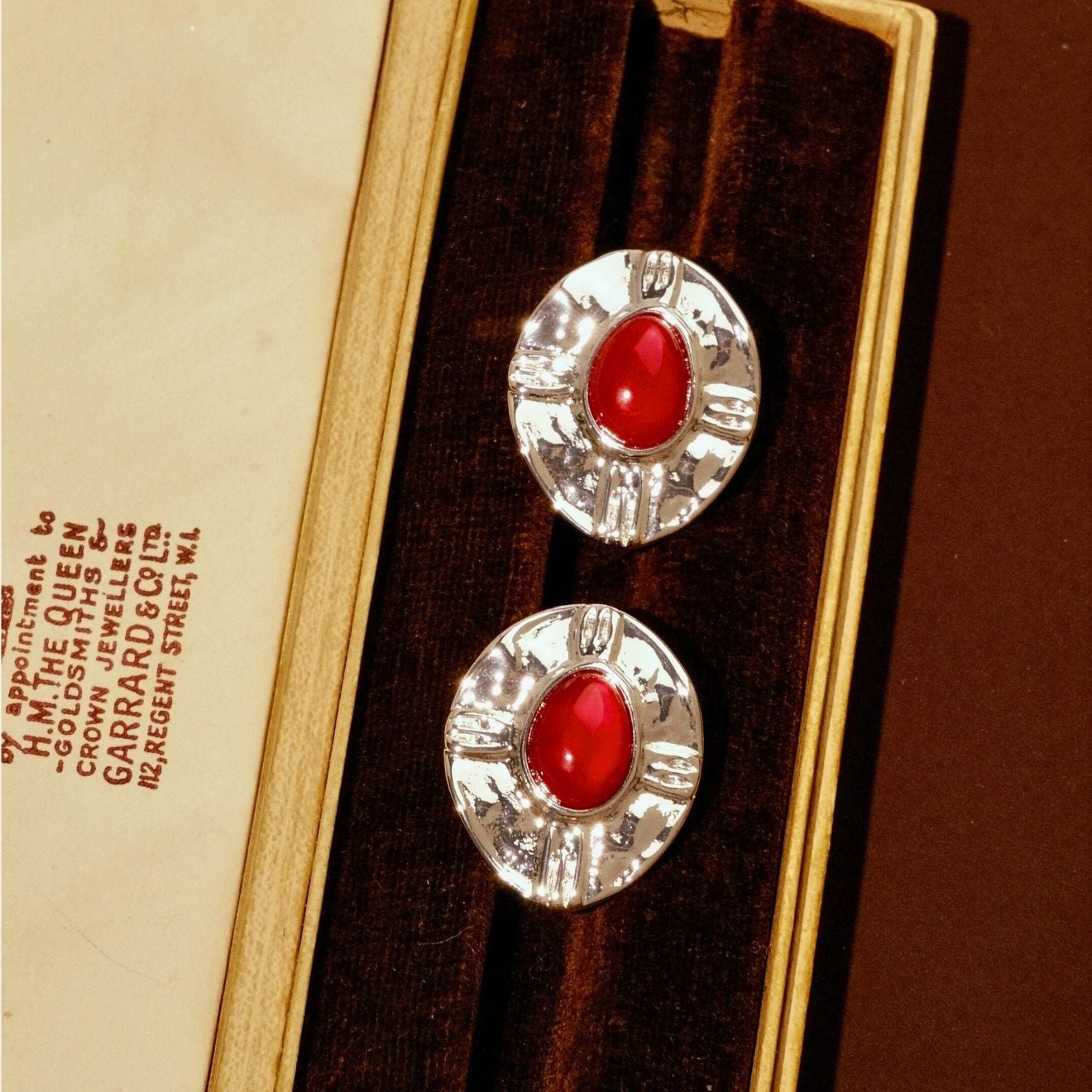Jinherit Brave Heart red agate and vintage-silver stud earrings displayed in a jewelry box, featuring oval red agate cabochons, hammered silver-plated frames, and a bold medieval-inspired look.