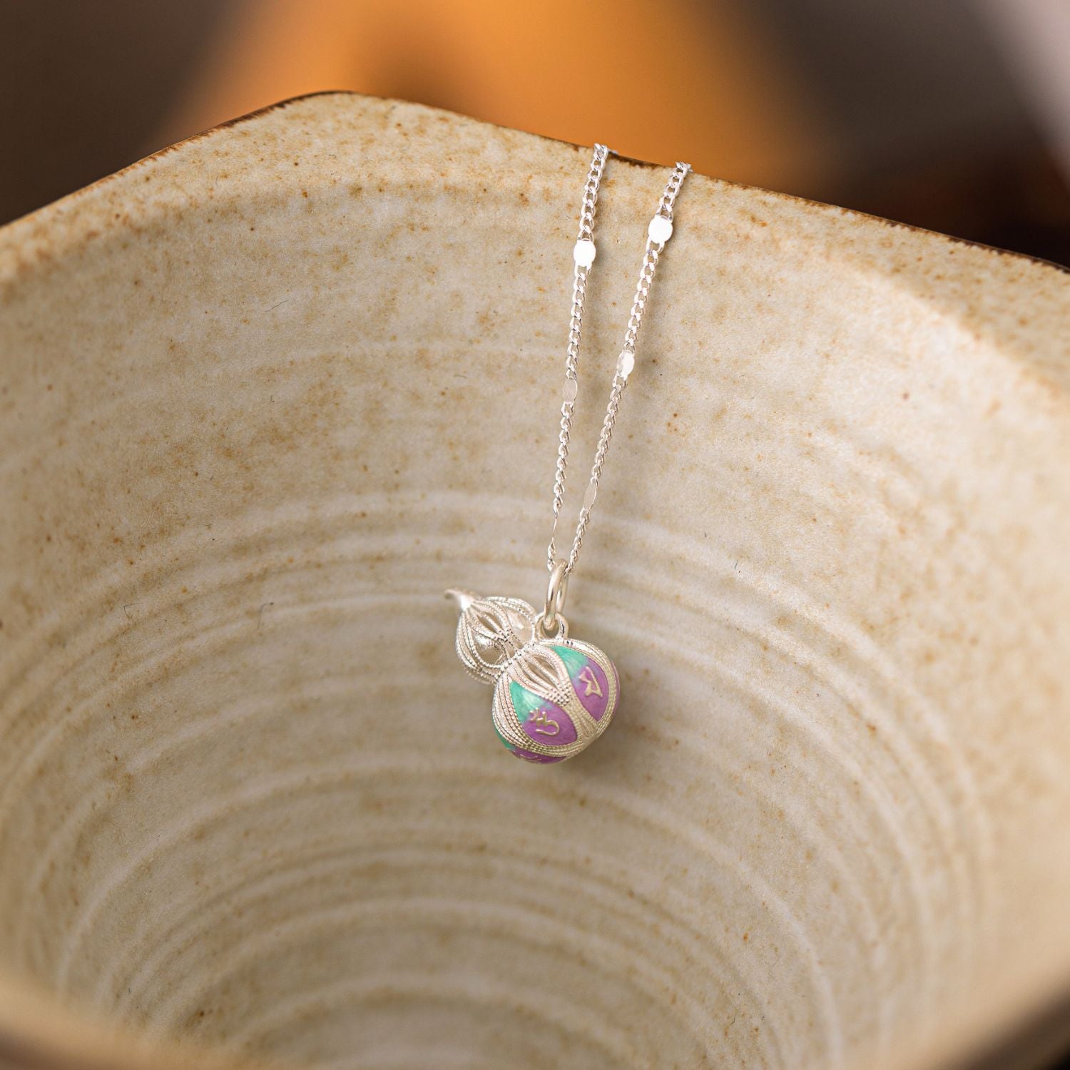 Jinherit Celestial Haze cloisonné enamel gourd necklace displayed on natural wood, highlighting the soft teal and lavender enamel, silver chain, and meaningful hulu motif.