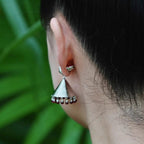Jinherit Crimson Echo garnet bell drop earrings worn by a model, showing the sculptural drop shape, subtle garnet movement, and heritage-inspired statement styling.