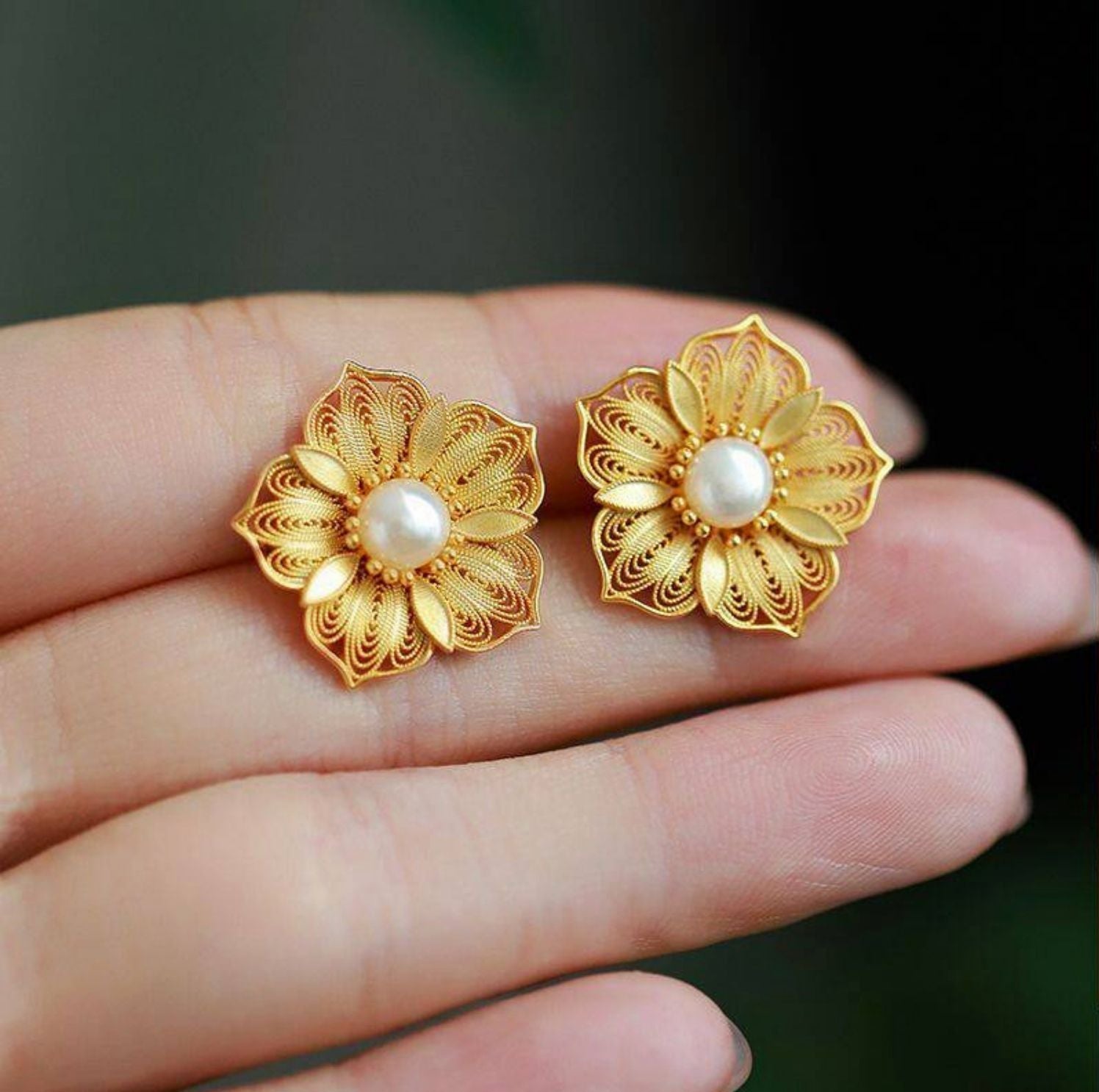 Jinherit Golden Bloom gold-plated filigree flower studs shown in hand, highlighting the compact stud size, sculptural petal texture, and refined freshwater pearl detail.