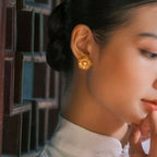 Jinherit Golden Bloom filigree pearl flower studs worn by a model, featuring gold-plated floral openwork, freshwater pearl centers, and elegant botanical styling.