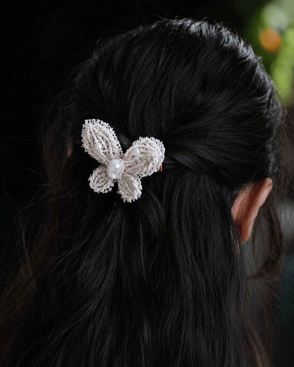 Pearl Flutter hand-beaded butterfly hair clip styled in black hair, pearl beaded hair accessory.