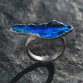 Jinherit Into the Blue blue enamel silver open ring displayed on dark stone, featuring a vivid lake-blue enamel surface, hand-forged S925 silver band, and organic shoreline-inspired form.