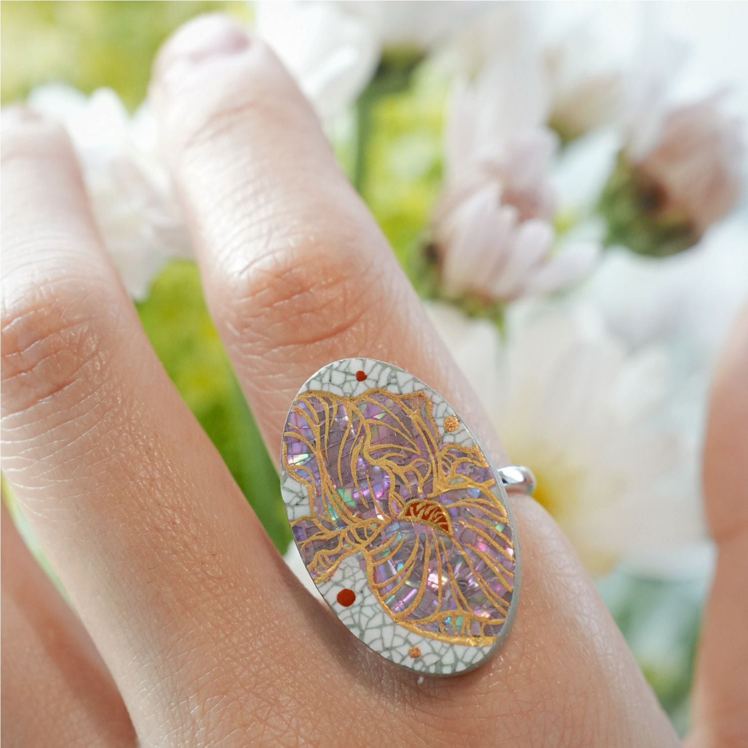 Jinherit Iris Reverie lacquer inlay ring worn on hand, showing the oval statement face, mother-of-pearl iris design, eggshell mosaic, and adjustable S925 silver ring band.