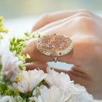 Jinherit Iris Reverie mother-of-pearl lacquer ring worn among flowers, highlighting the botanical iris motif, gold foil detail, soft shell shimmer, and wearable art character.