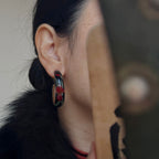 Jinherit Iris Thicket black Chinese lacquer hoop earrings worn by a model, showing the sculptural C-hoop shape, hand-painted iris motif, and refined heritage-inspired styling.