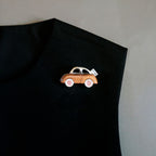 Jinherit Joyride wooden car brooch worn on a black top, showing its playful car silhouette, warm wood texture, and creative statement styling for everyday outfits.