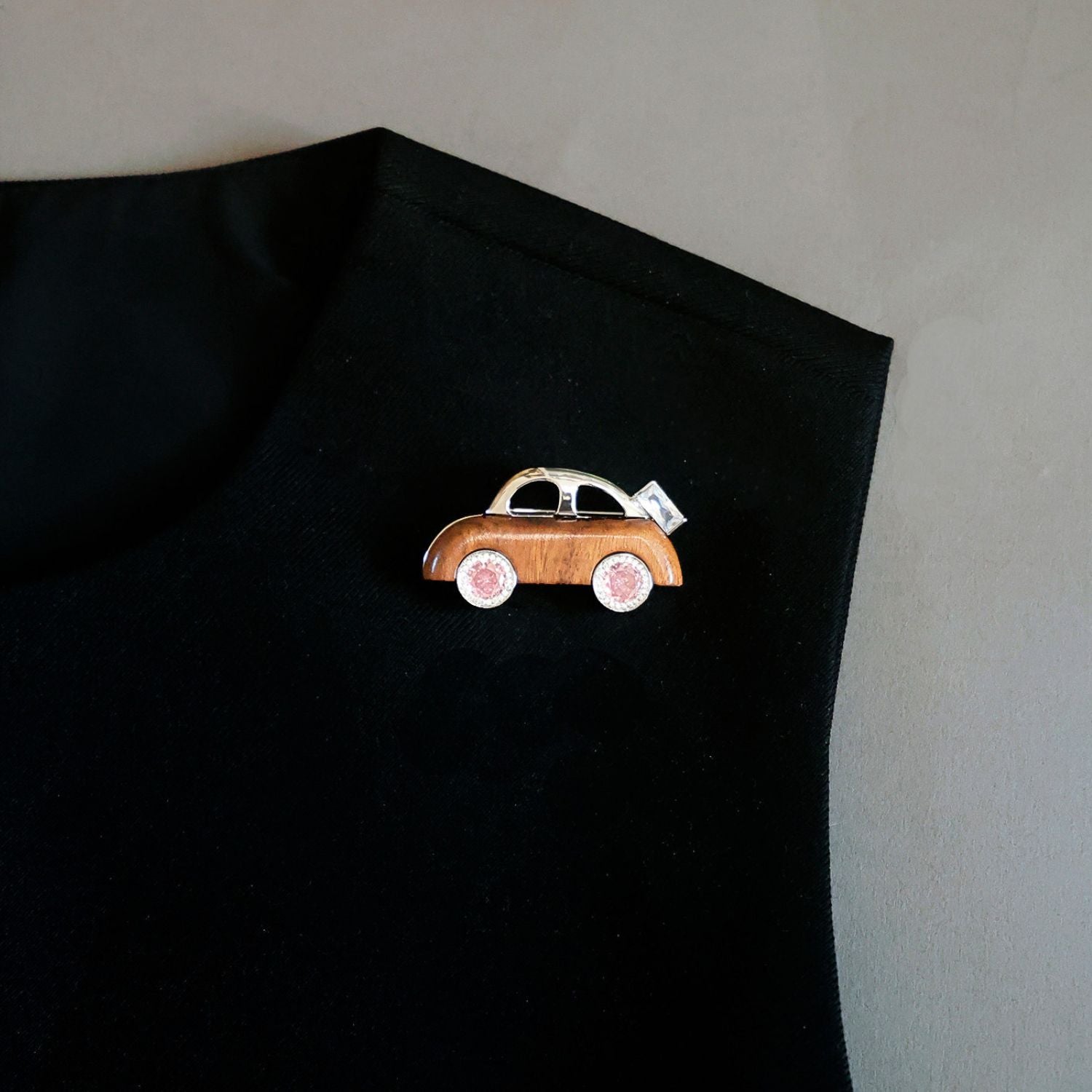 Jinherit Joyride wooden car brooch worn on a black top, showing its playful car silhouette, warm wood texture, and creative statement styling for everyday outfits.