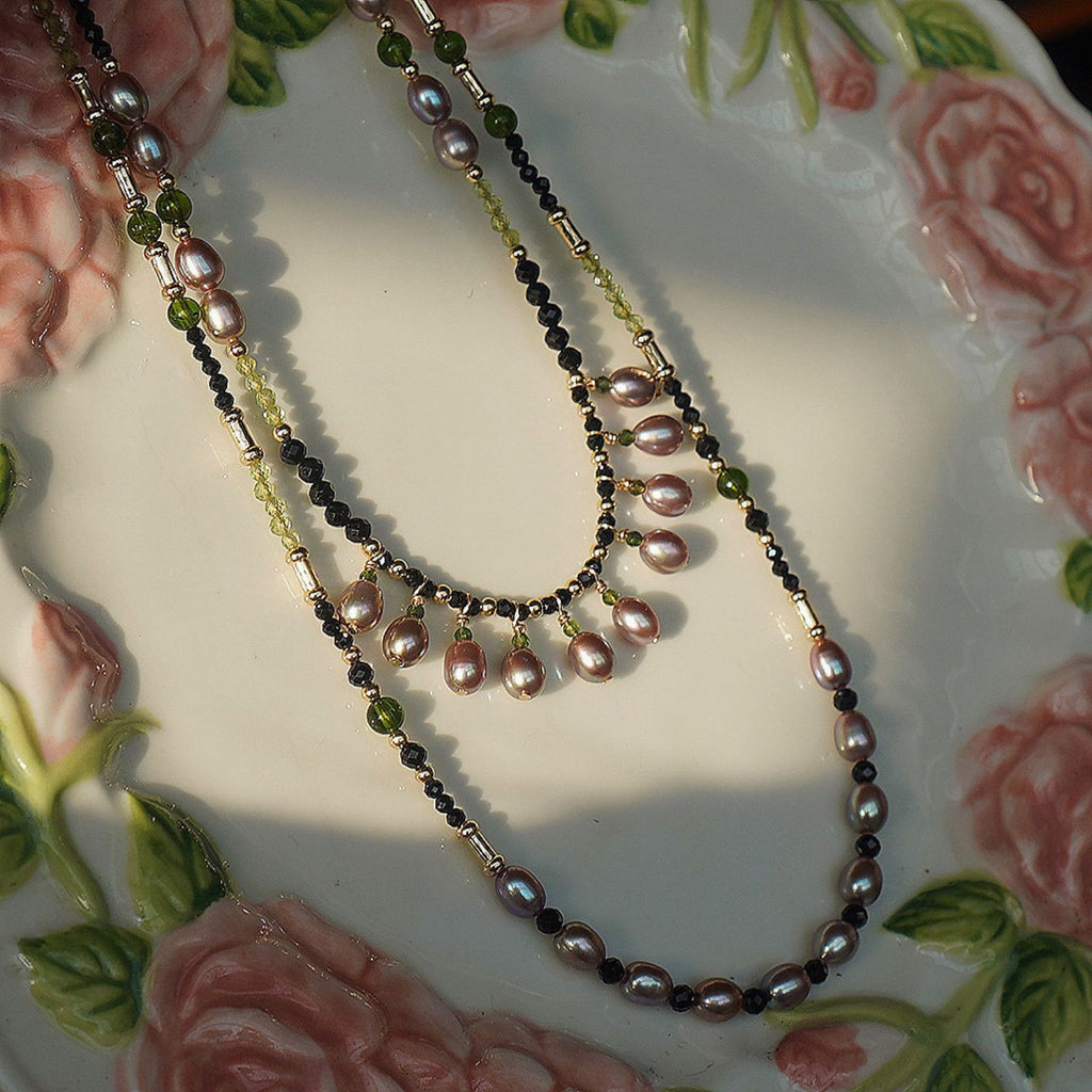 Jinherit Lustrous Tide convertible pearl tassel wrap necklace styled as a flat lay, featuring cascading freshwater pearl drops, black spinel depth, green stone accents, and antique-inspired layering.