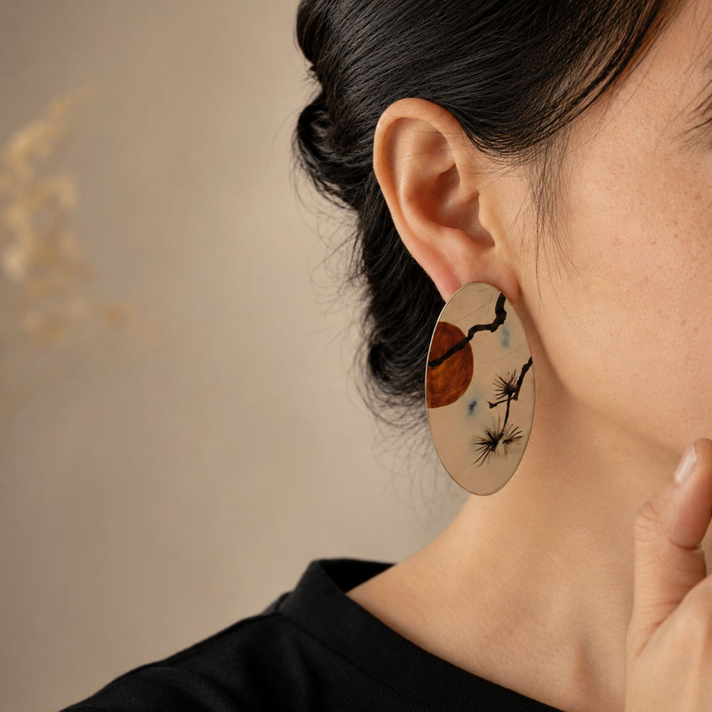Jinherit Pine & Moon hand-painted Chinese lacquer drop earrings worn by a model, showing the bold oval shape, face-framing length, pine and moon landscape motif, and heritage-inspired styling.