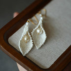 Jinherit Pure Calla beaded calla pearl drop earrings displayed in a jewelry box, featuring hand-beaded white seed beads, calla lily-inspired petals, and freshwater pearl drops.