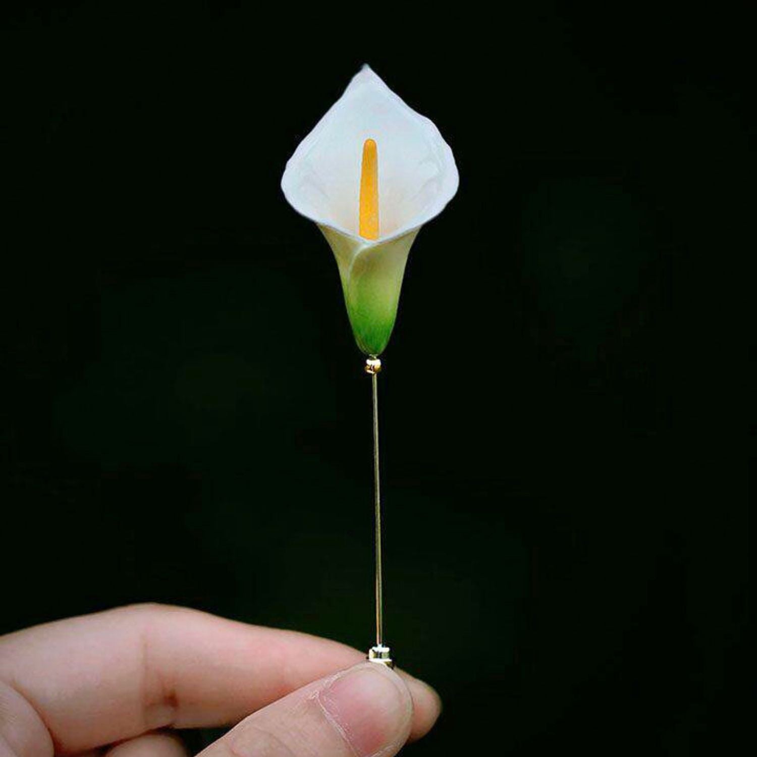 Jinherit Quiet Bloom ceramic calla lily brooch pin shown in hand, highlighting its wearable scale, sculptural floral shape, and delicate botanical detail.