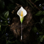 Jinherit Quiet Bloom ceramic calla lily brooch pin displayed on a dark botanical leaf background, featuring a white floral head, green detail, and slender lapel pin design.