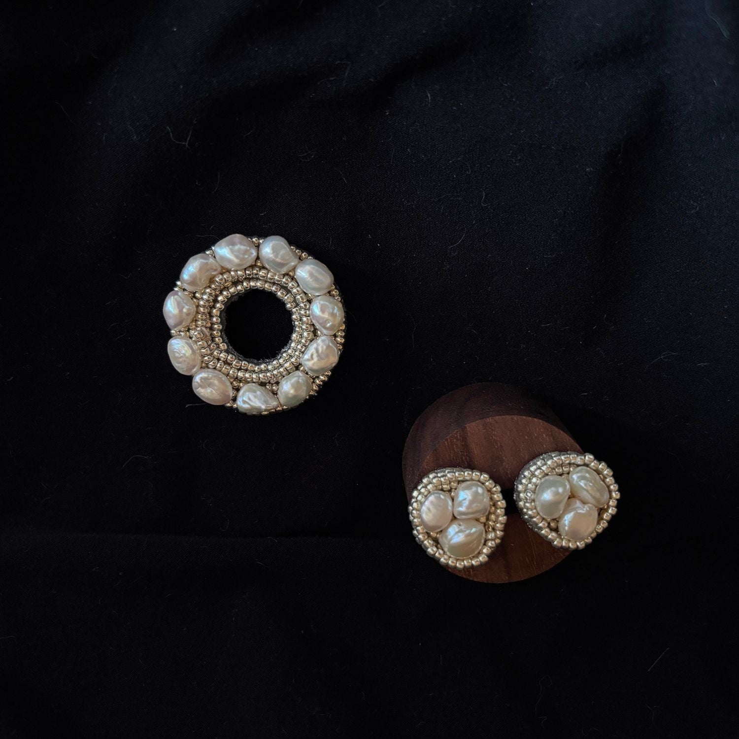 Jinherit Silver Halo baroque pearl embroidered brooch pin styled on black fabric, showcasing its sculptural beadwork, organic pearl texture, and quiet luxury appeal.
