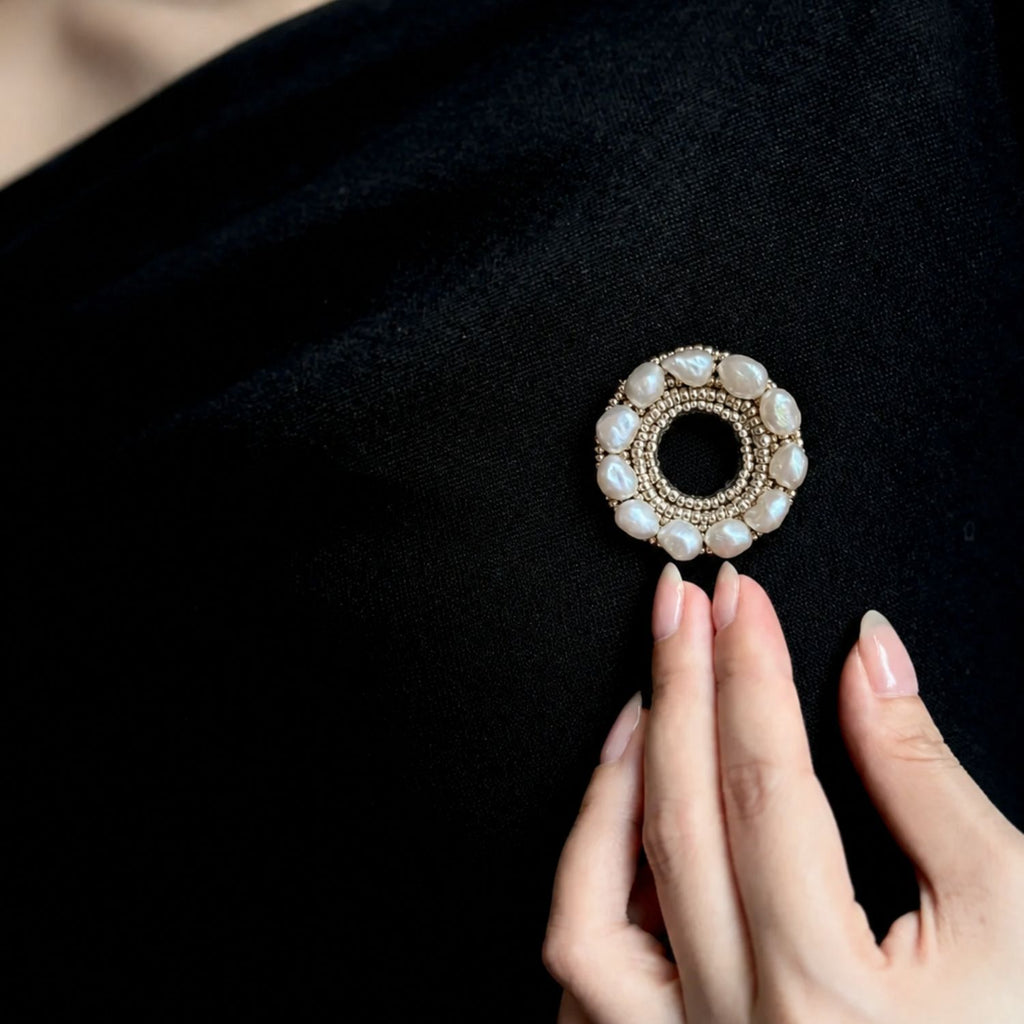 Jinherit Silver Halo baroque pearl embroidered brooch pin shown in a real wearing detail, highlighting its circular silhouette, pearl luster, and refined handmade texture.