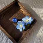 Jinherit Sky Bloom Ronghua silk flower hair clip detail in a wooden box, highlighting the layered blue floral form, soft silk texture, and handmade botanical craftsmanship.
