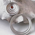 Jinherit Still Ripple matte silver-tone carnelian stud earrings detail view, highlighting the concentric ripple construction, crimson carnelian centre, and convertible design for versatile styling.