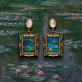 Jinherit Water Lily Dream feather inlay drop earrings on a water lily painting-inspired background, featuring iridescent feather inlay, mother-of-pearl tops, and gold-plated framed details.