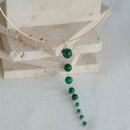 Jinherit Zen Line emerald-green Y-drop lariat necklace flat lay, showcasing a gold-plated collar arc and a long vertical drop of graduated emerald-green beads in a modern minimalist design.