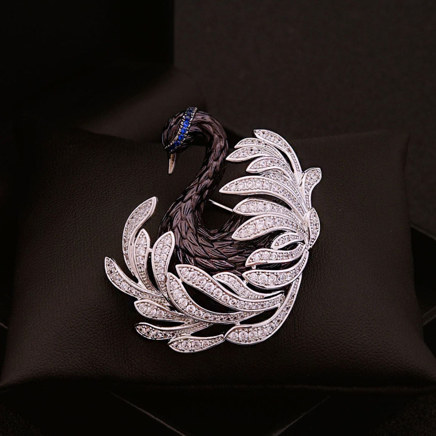 Close-up of black swan crystal brooch with sculptural feather lines, zircon stones, and midnight blue accents.