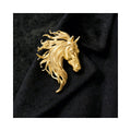 The Gallant Spirit gold horse brooch on black fabric, featuring a sculpted horse head, flowing mane, and vintage equestrian elegance.