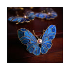 Full front view of Whispering Wings Dian Cui butterfly brooch highlighting symmetrical butterfly wings, pearl center, and structural iridescence.