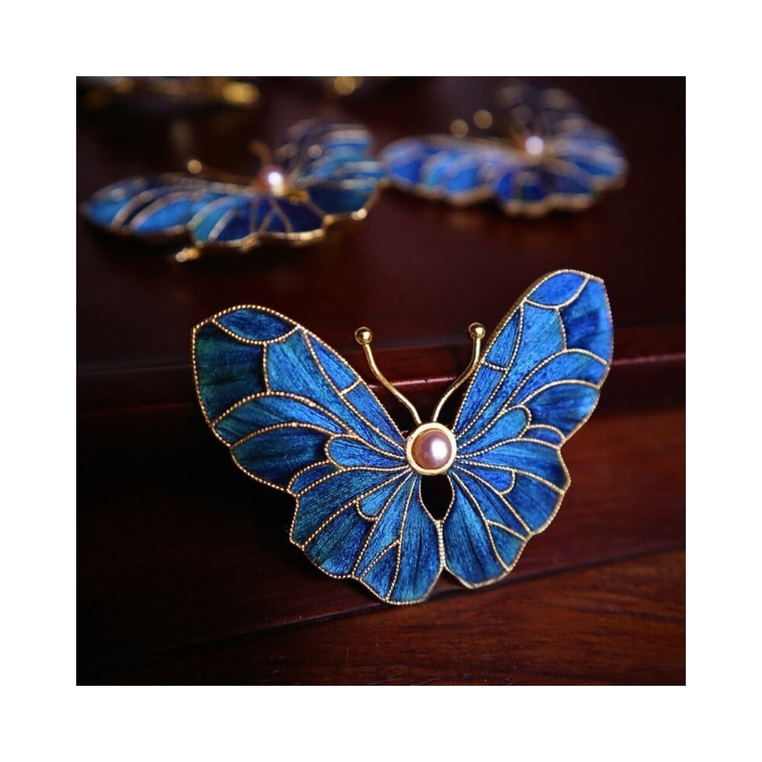 Full front view of Whispering Wings Dian Cui butterfly brooch highlighting symmetrical butterfly wings, pearl center, and structural iridescence.