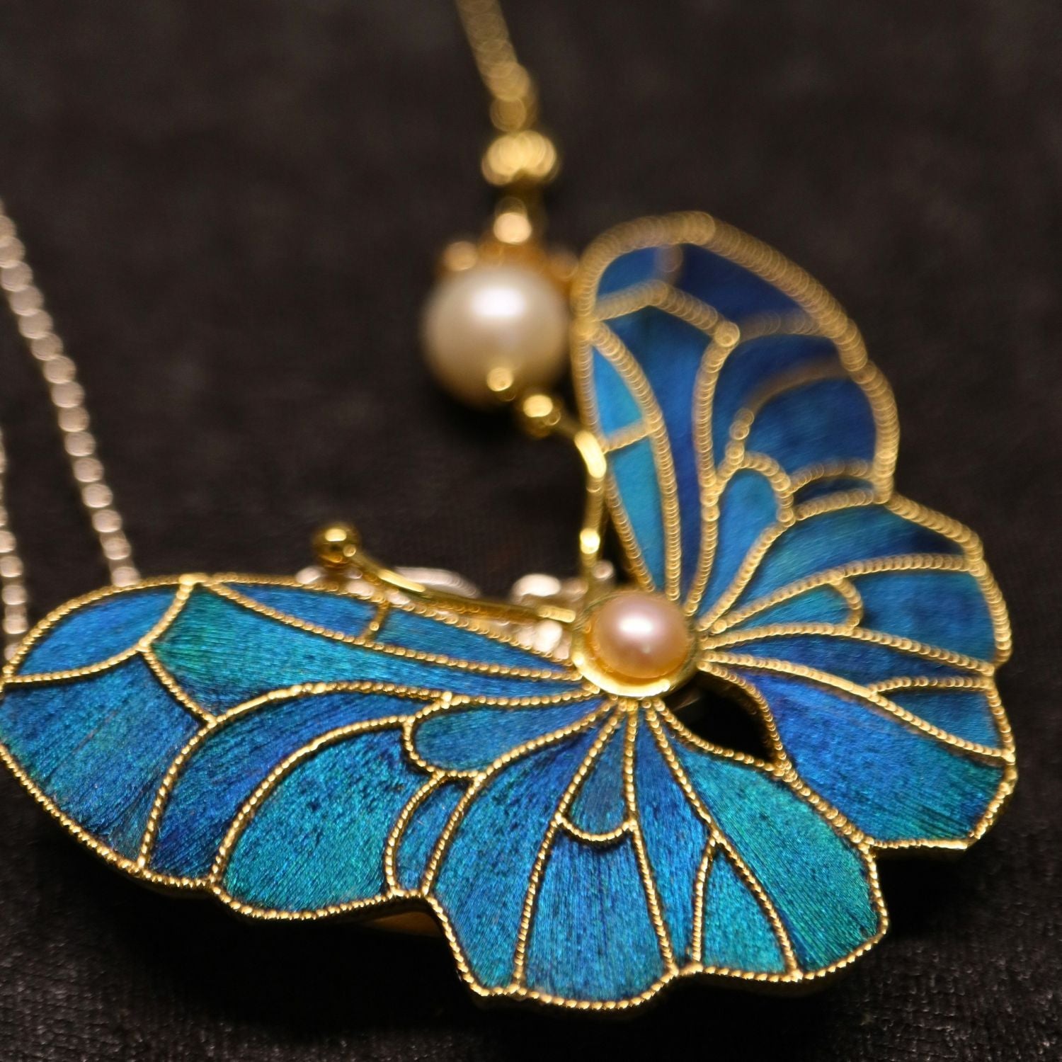 Whispering Wings Dian Cui-inspired butterfly brooch with peacock-feather inlay, gold-toned lines, and freshwater pearl detail.