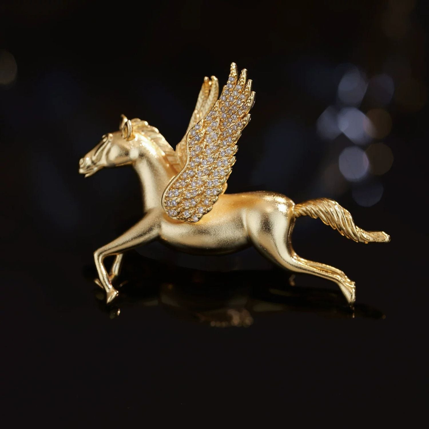 Gold-tone Pegasus brooch with sculpted winged horse form and pavé cubic zirconia accents.