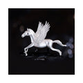 Close-up of Wings of Inspiration Pegasus pavé horse brooch in silver tone on a dark background, featuring the sculpted horse silhouette, pavé wing sparkle, and cool-toned shine.